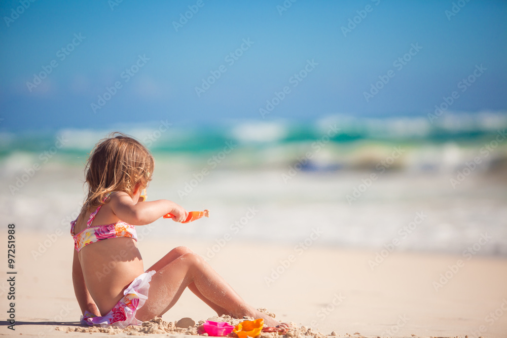 Adorable little girl playing with beach toys during tropical vacation