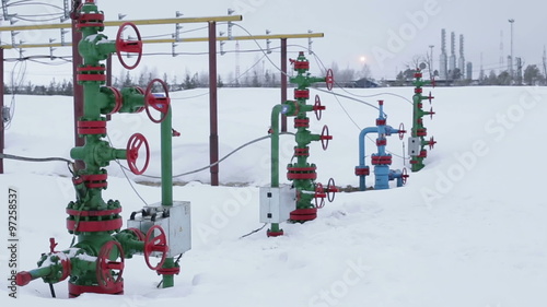The valves at the wellhead production. In the background processing plant gas and oil