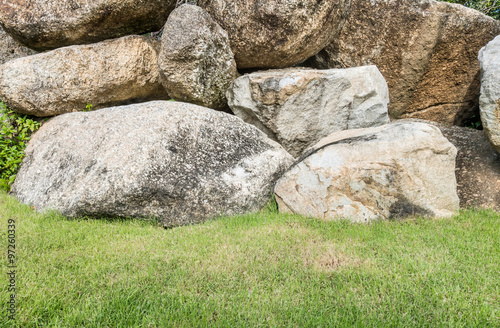 Closeup group of big rock for decorate with green grass in the garden texture background