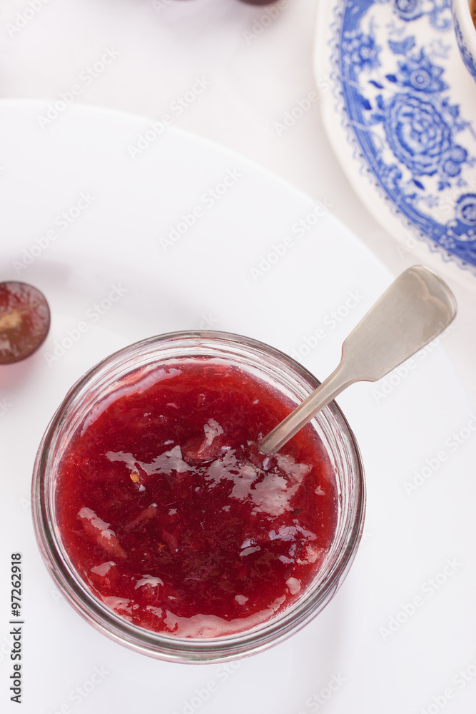 Jam with red grape in a glass jar on a white background. Closeup. Jam with red grape in a glass jar on a white background. Closeup.