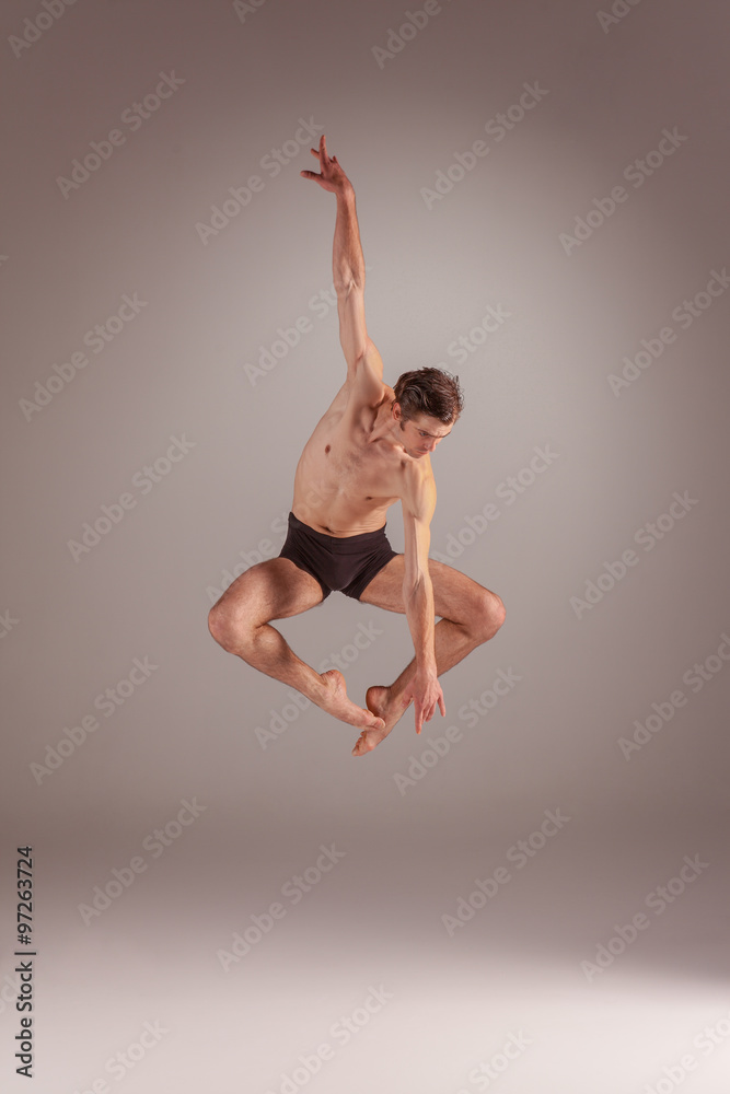Fototapeta premium The young attractive modern ballet dancer jumping on gray background