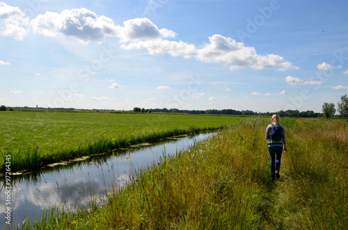 Girl walking on a small trail next to a ditch in Dutch polder