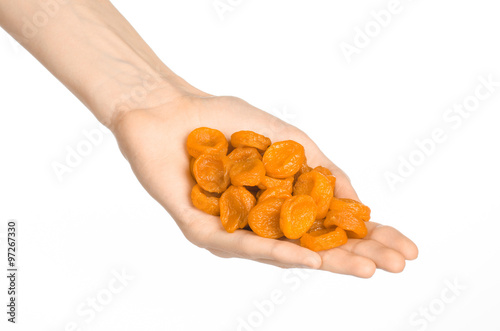 Dried fruits and meal preparation topic: human hand holding an orange dried apricots isolated on white background in studio