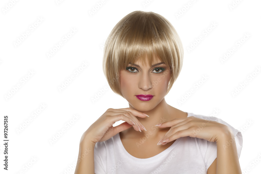 serious young woman with short blonde wig posing on a white serious young woman with short blonde wig posing on a white