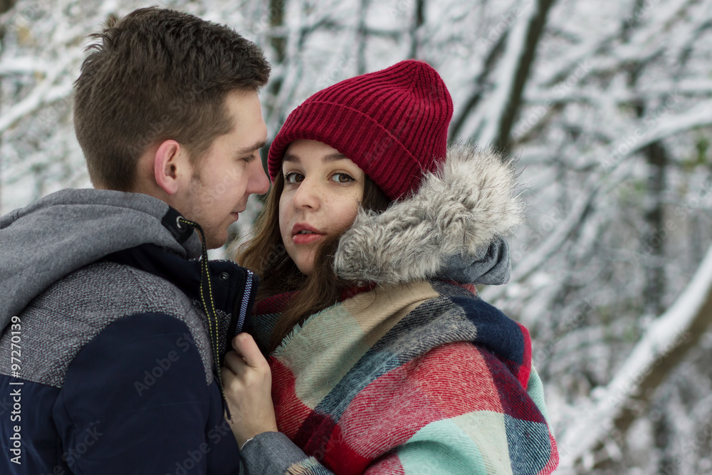 Cute guy and beautiful girl hugging in winter park