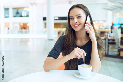 woman drinking coffee and calling with cellphone