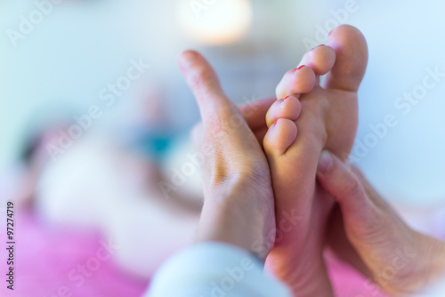 Therapist's hands massaging female foot photo