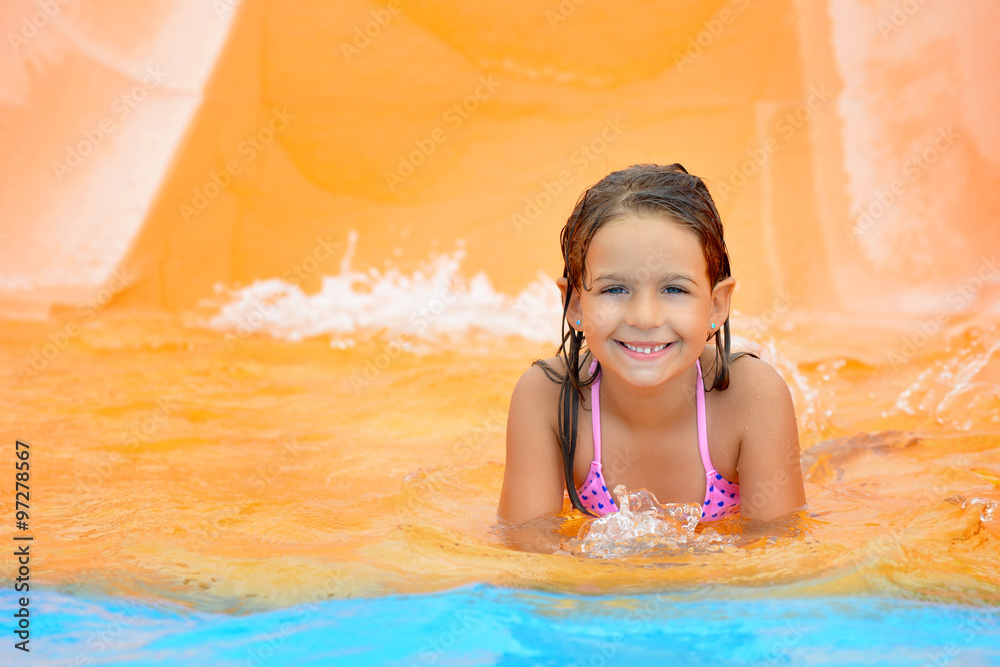 Adorable toddler girl on water slide at aquapark Adorable toddler girl on water slide at aquapark