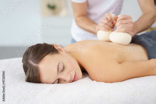 frau entspannt bei einer massage mit kräuterstempeln