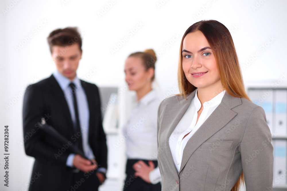 Pretty businesswoman in office with colleagues in the background Pretty businesswoman in office with colleagues in the background