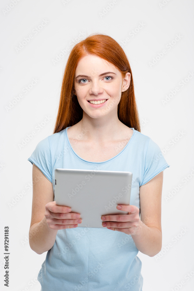 Pretty smiling redhead lady with long hair using tablet isolated
