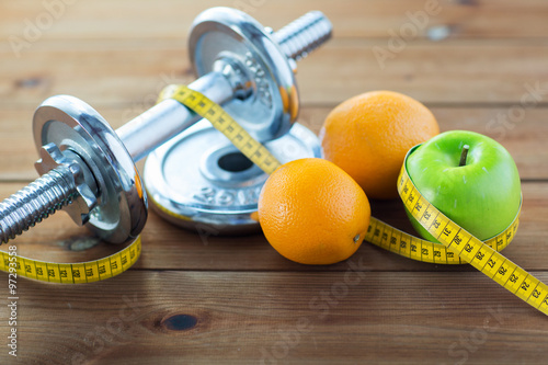 close up of dumbbell, fruits and measuring tape