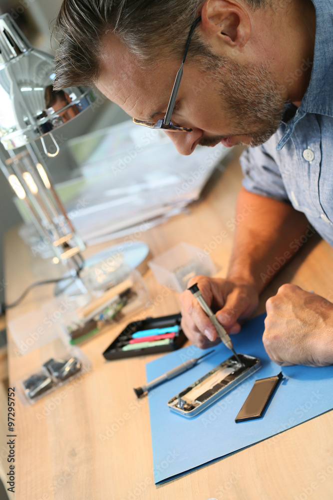 Man repairing broken smartphone in workshop