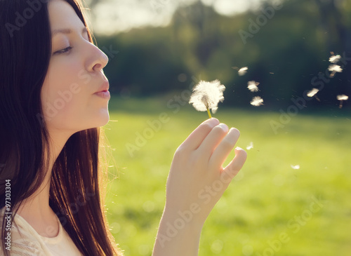 woman blowing on a dandelion