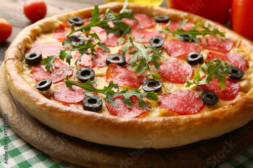 Tasty pizza with salami on decorated wooden table
