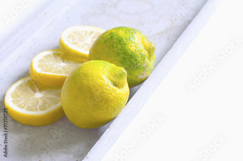 Two lemons with three slices of lemon on a plate