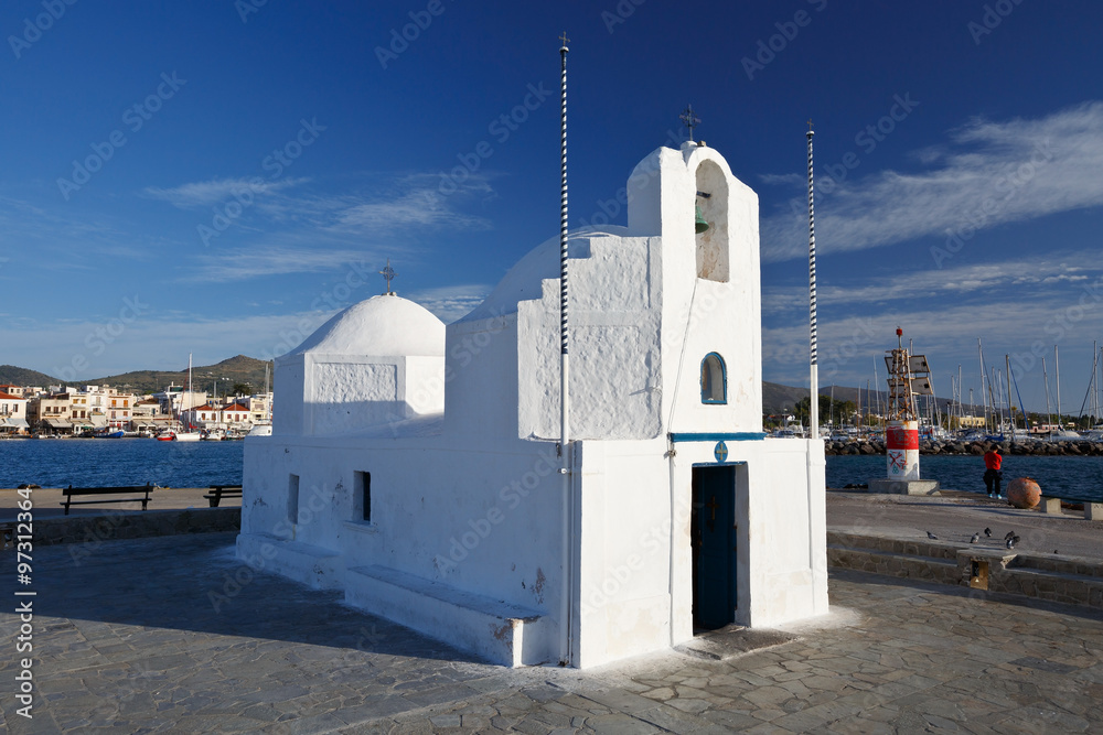 Small church in the harbour and view of Aegina town behind it, Greece