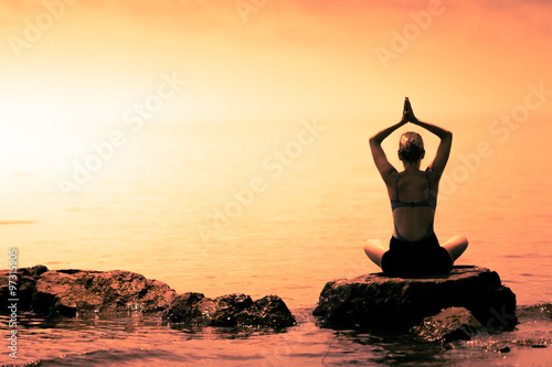 Young Woman doing Lotus Yoga Position in Front of the Ocean