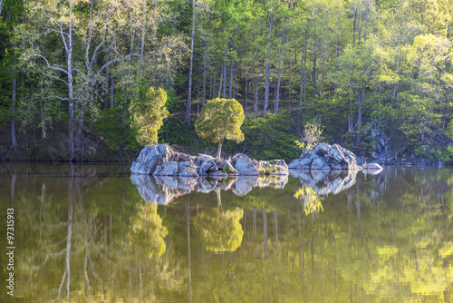 A small island and trees in the reflected in the calm surface of the Widewater area of the C&O Canal National Historic Park, Potomac, Maryland.