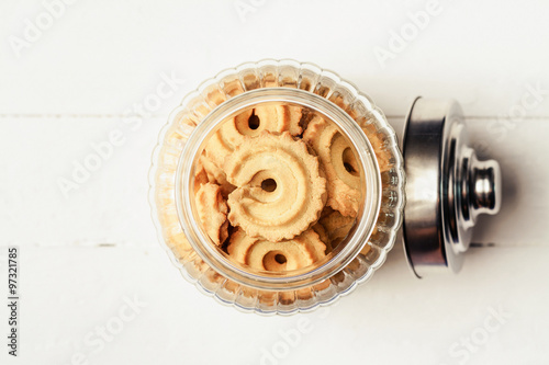 Overhead view of danish butter cookies in a glass jar on tablecl