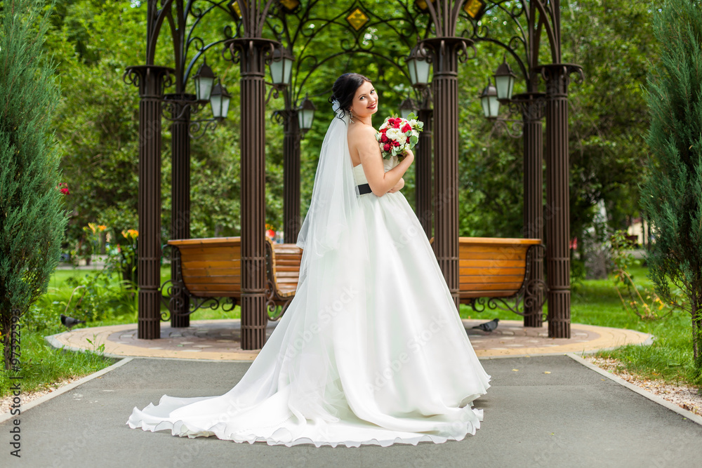 Bride with bouquet near wooden pavilion