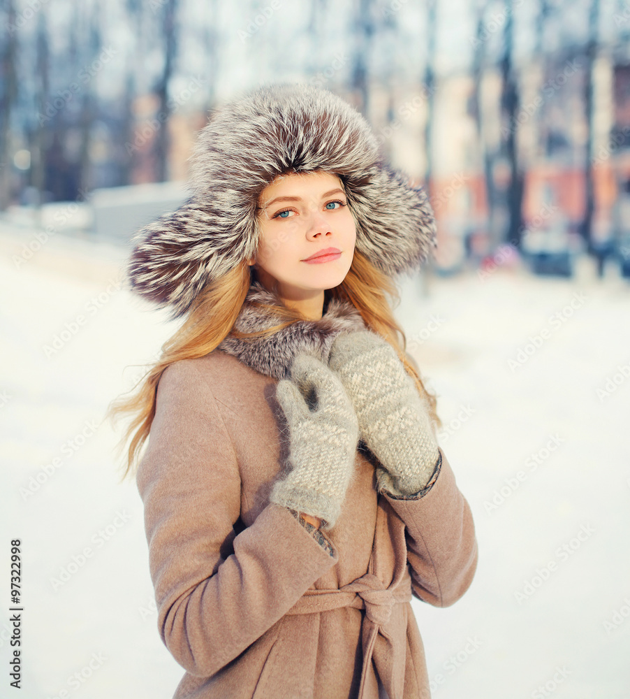 Beautiful happy smiling woman wearing a coat and hat over snow i Beautiful happy smiling woman wearing a coat and hat over snow i