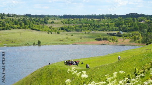 Tourists at the coast of the lake near the ancient Izborsk photo