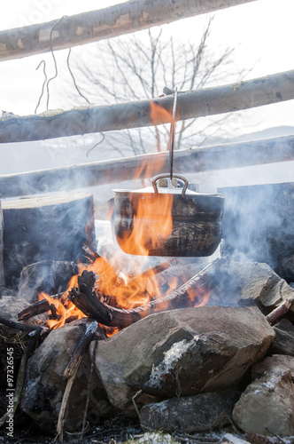 Cooking in field conditions  boiling pot at the campfire on picnic  mountains  
