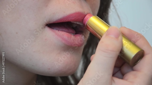 Девушка красит пухлые губы губной помадой, крупный план.