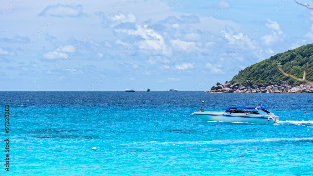 White speed boat was running slowly on the blue sea surface in front of Koh Miang Island under the summer sky and beautiful nature in Mu Ko Similan National Park, Phang Nga, Thailand, 16:9 wide screen