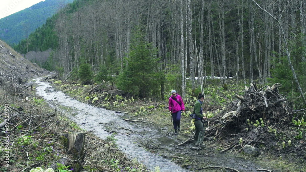 two female hikers walking along the mountain stream slow motion two female hikers walking along the mountain stream slow motion
