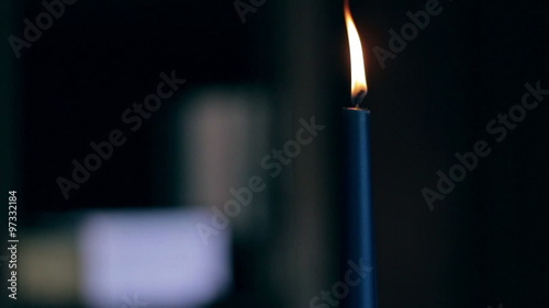 Closeup of a blue burning candle flickering and being blown out