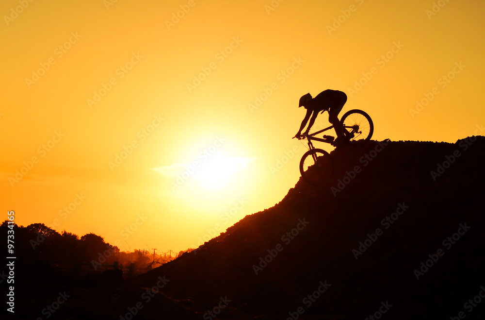 A cyclist riding down the hill with sunset silhouette A cyclist riding down the hill with sunset silhouette