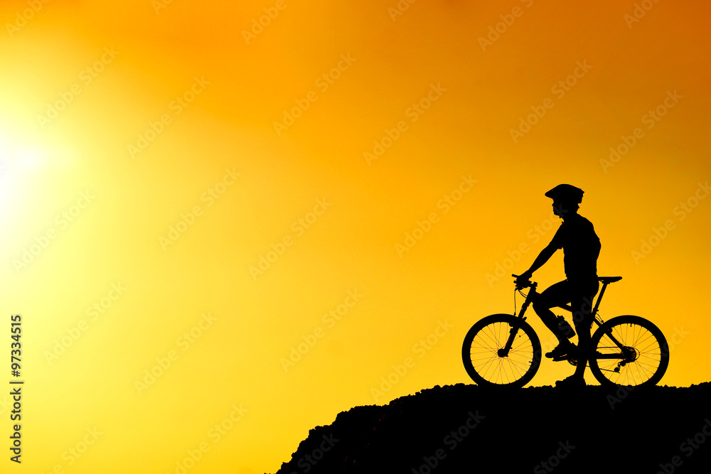 A cyclist on the hill with sunset silhouette