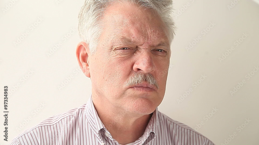 A senior man chews a piece of gum.