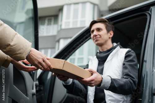 Giving postal box by smiling courier into woman's hands