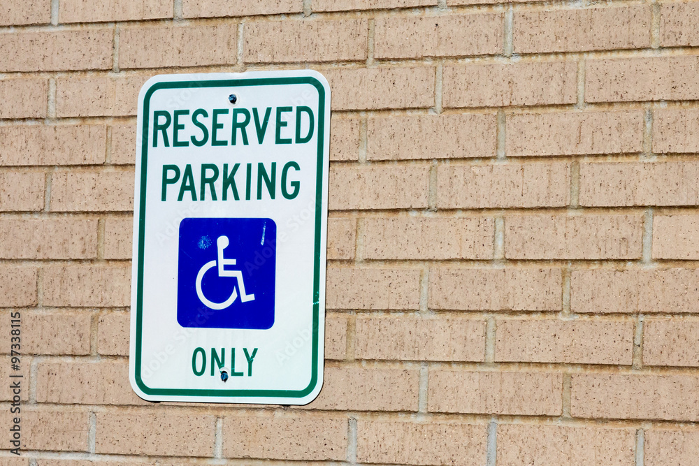 Reserved handicapped parking sign on the brick wall of a business Reserved handicapped parking sign on the brick wall of a business