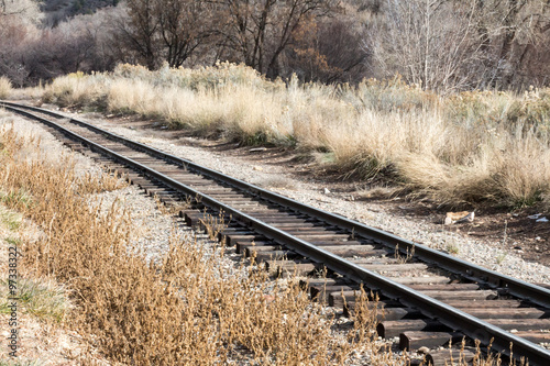 Train tracks through dry, brown grass