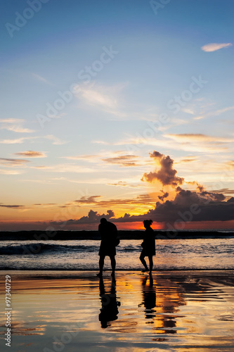 Silhouette lovers relax on the beach in color of sunset