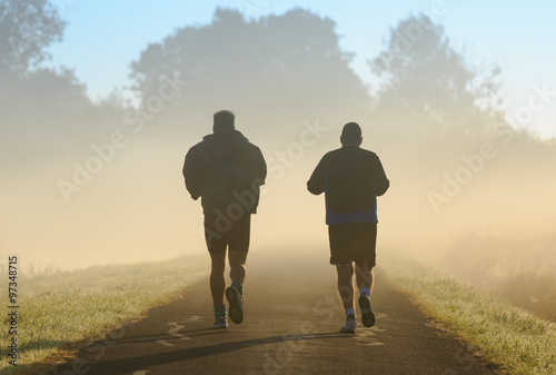 Two men running in the morning fog.
