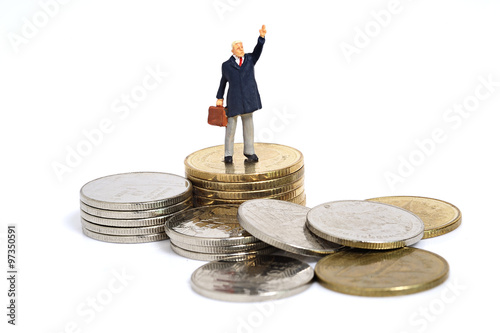 Miniature business man stand on coins