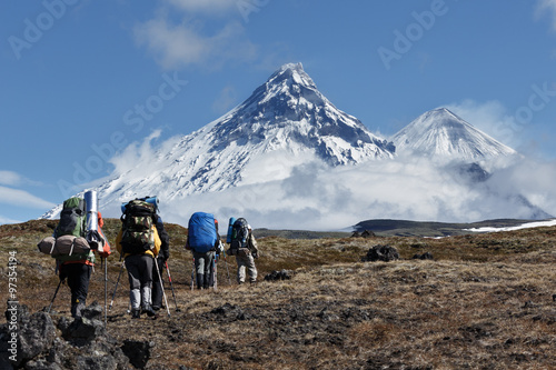 Hiking on Kamchatka: travelers go to mountains on background of volcanoes
