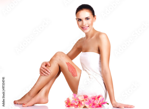 Beautiful young smiling woman with flowers using a scrub.