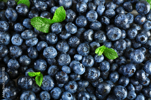 Tasty ripe blueberries with green leaves close up