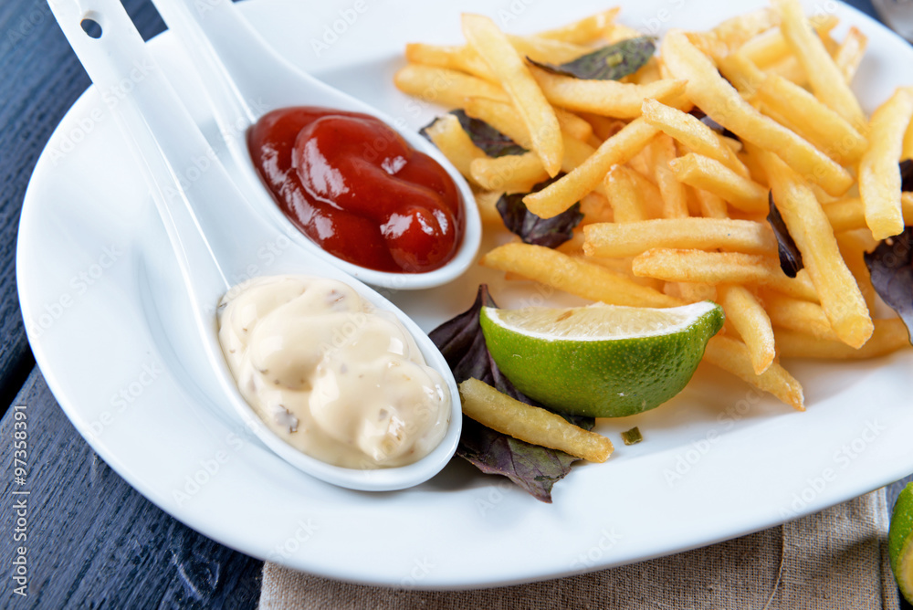 French fried potatoes with sauce and lime on white tray French fried potatoes with sauce and lime on white tray