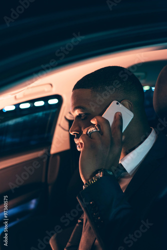 Businessman in car calling with smartphone.