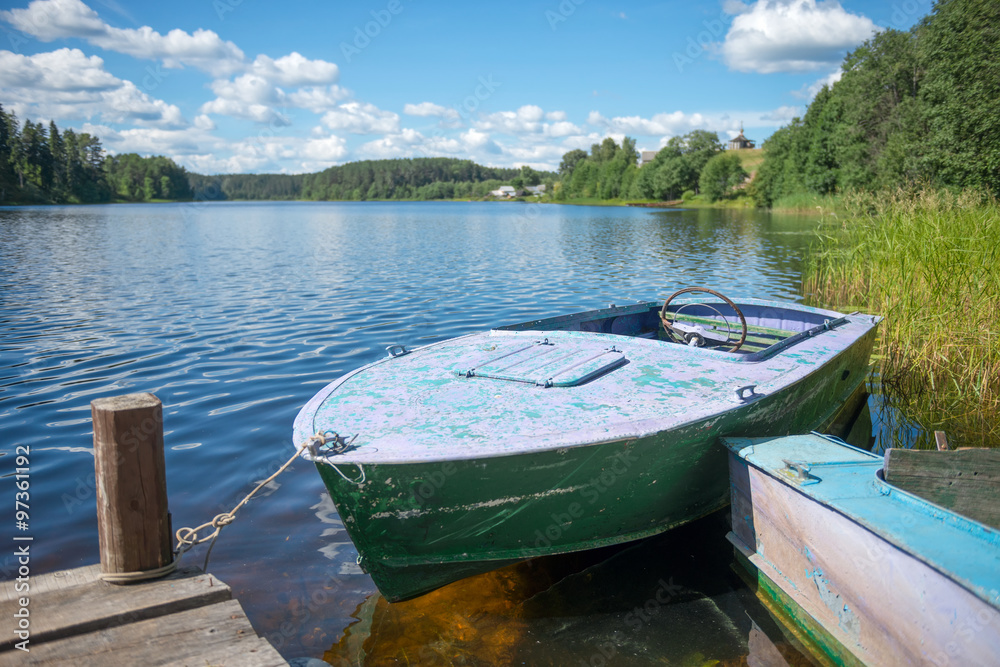 Old motor boat tied to a wooden pier on the lake Old motor boat tied to a wooden pier on the lake