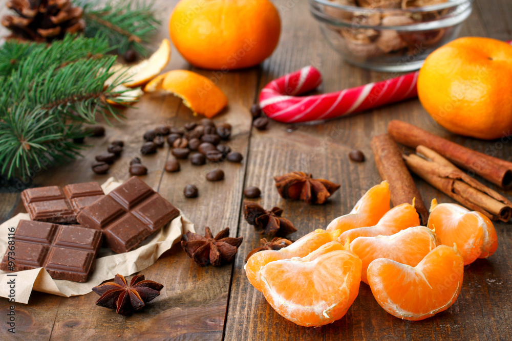 tangerines with chocolate and Christmas candy lying near a spruce branch with cone on wooden background