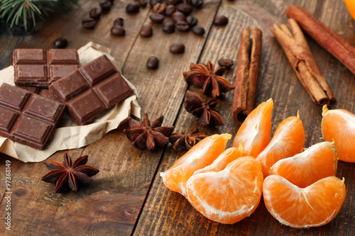 tangerines with chocolate and coffee beans near spruce branches on wooden background