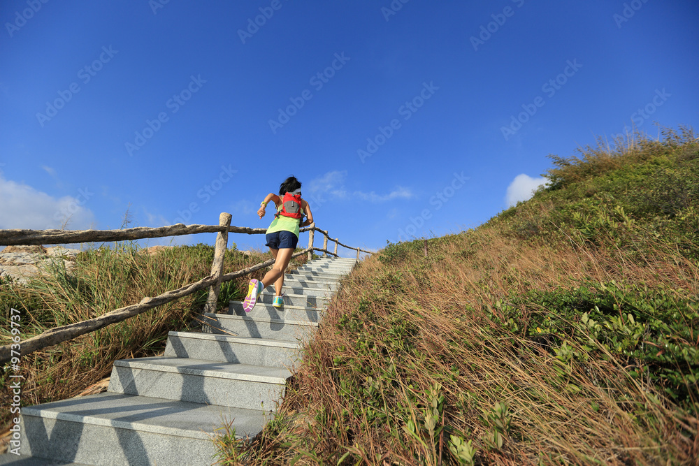 young fitness woman trail runner running up on mountain stairs